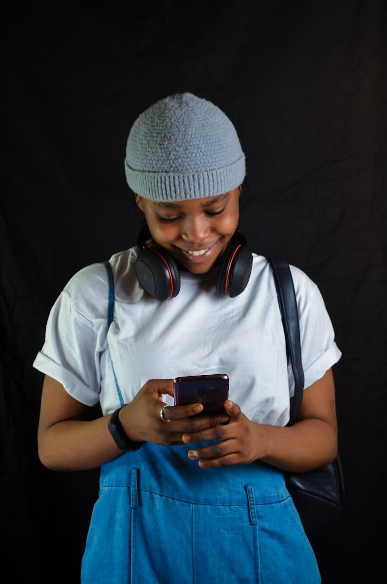 a young person wearing headphones and holding a cell phone
